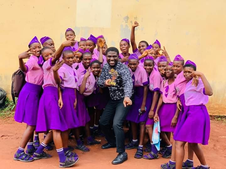 Teacher Chike poses with his students as he displays an award.